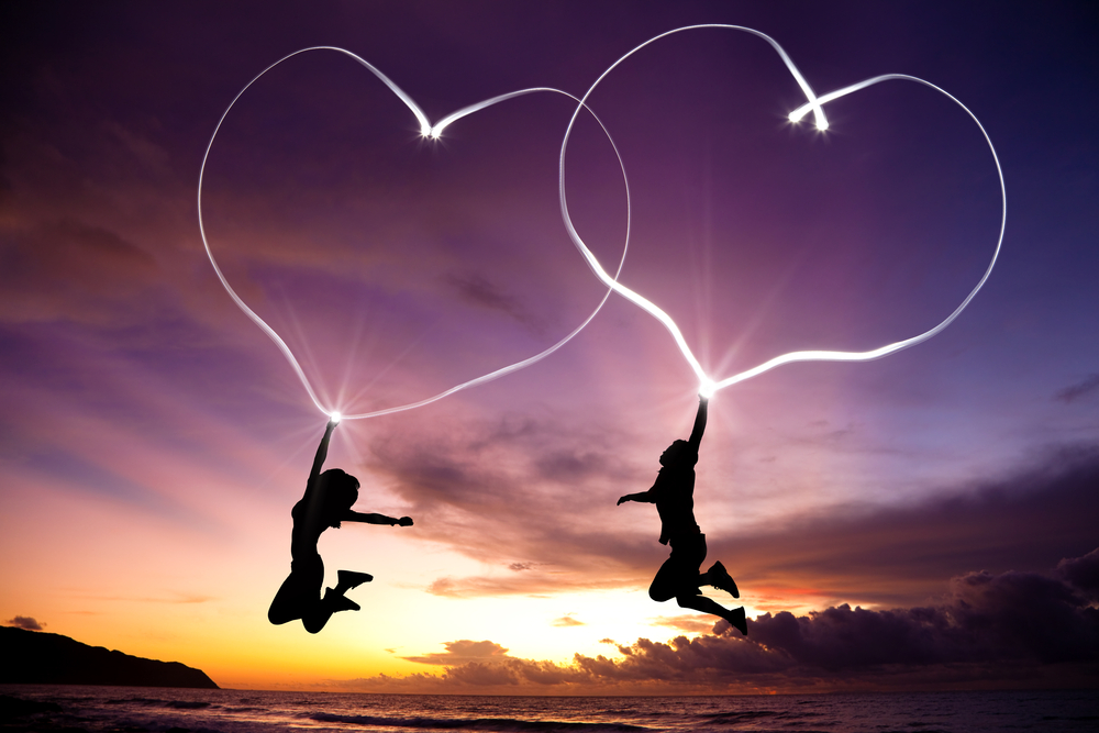 young couple jumping and drawing connected hearts